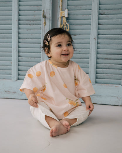 Baby wearing Wildgreen’s Apricot T-shirt from the Island Life collection. Made from 100% GOTS-certified organic cotton, this gender-neutral kids’ tee features a soft apricot-hued print, perfect for eco-conscious families seeking sustainable and stylish clothing. #OrganicKidswear #SustainableFashion